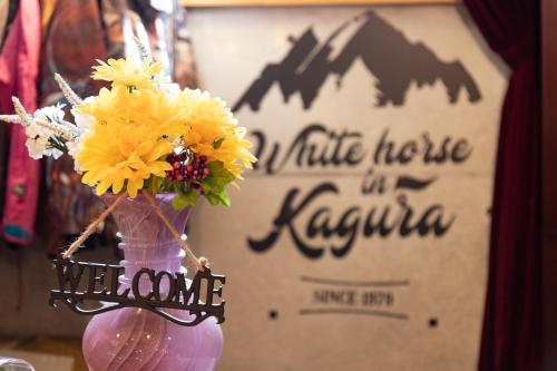 a purple vase with yellow flowers in front of a sign at Kagura White Horse Inn in Yuzawa