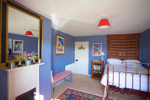 een slaapkamer met blauwe muren en een bed en een spiegel bij Beautiful Devon Farmhouse in Exeter
