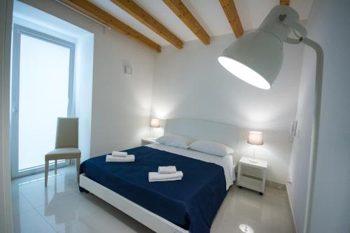 a white bedroom with a blue bed and a large window at Palazzo di Fazio Suites in San Severo