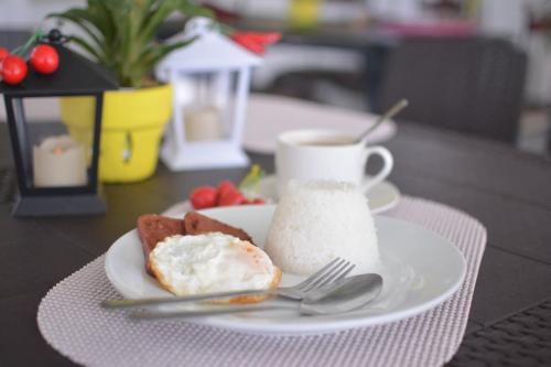 a plate with a piece of cake and a cup of coffee at Casa Bicolandia Suites in Daraga