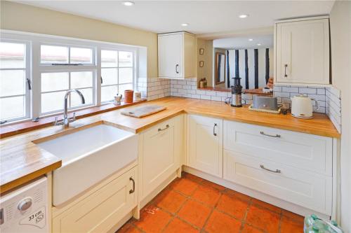 a kitchen with white cabinets and a sink at Best located and beautifully renovated cottage in Diss