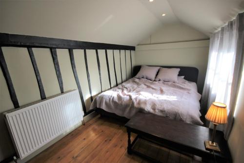 a small bedroom with a bed and a table at Best located and beautifully renovated cottage in Diss