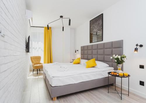 Un dormitorio con una cama con almohadas amarillas y una mesa. en Aaron Aparthotel, en Cracovia