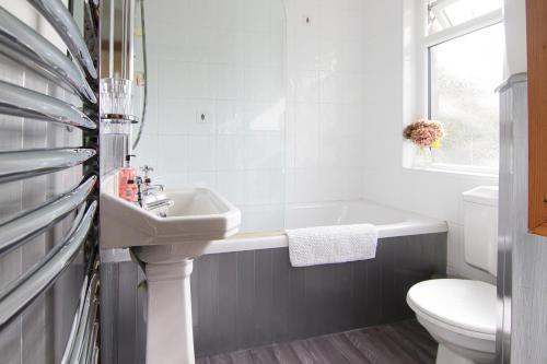 a bathroom with a sink and a tub and a toilet at Bridge End Cottage in Coniston