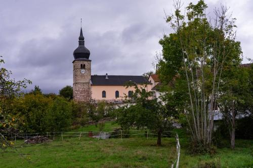 a building with a clock tower on top of a field at Gite Amélie, Sauna, Spa au coeur des Vosges in Housseras