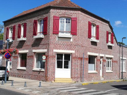 a red brick building with red shutters on a street at Halte en B in Noyelles-sur-Mer
