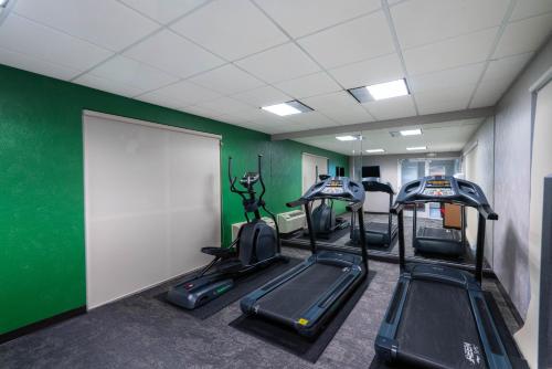 a gym with three tread machines and a green wall at Wingate by Wyndham Fletcher at Asheville Airport in Fletcher