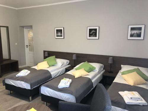 Habitación con 3 camas con almohadas verdes y amarillas en Villa Rosa, en Poznan