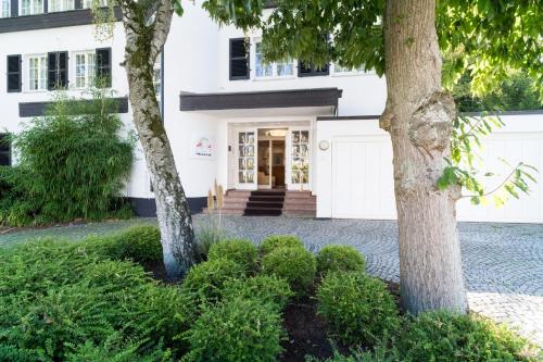 a white house with two trees in front of it at Hotel Villa im Park in Düsseldorf