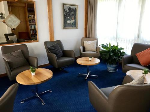 a waiting room with couches and chairs and tables at Hotel Parnass in Zermatt
