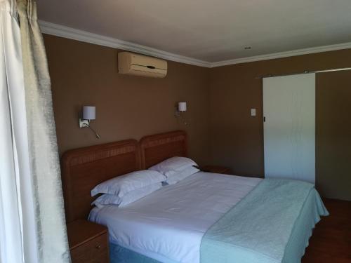 a bedroom with a bed with white sheets and a window at Letamong in Hartbeespoort