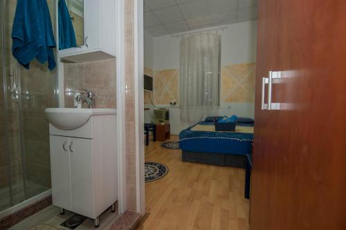 Un baño con lavabo y un dormitorio con cama. en Apartman Perper, en Trebinje