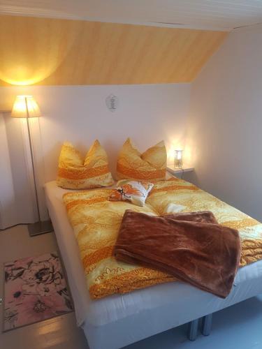 a bed with a blanket and pillows on it at Lille Villa Severin in Mosterhamn