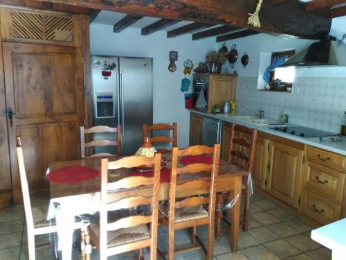 a kitchen with a wooden table and chairs and a kitchen with a refrigerator at CHAMBRE A LA CAMPAGNE - CHARENTE in La Rochette