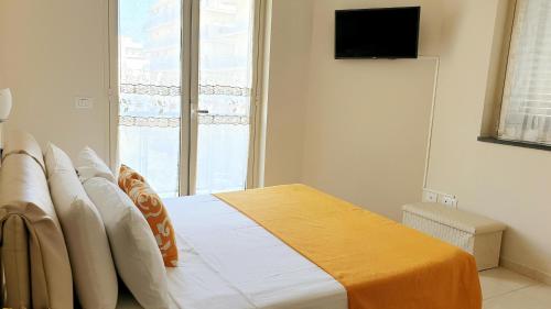 a bedroom with a bed with an orange blanket and a window at Nerissa Holiday Apartment Milazzo in Milazzo