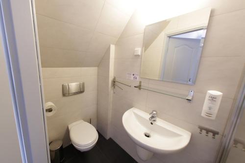 a bathroom with a sink and a toilet and a mirror at Hotel Nad Stawem in Bogacica