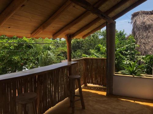 a porch with two stools and a wooden pergola at Cuarto de Tim in Mazunte