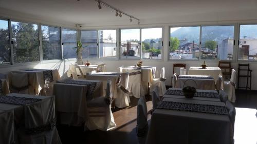 a room with white tables and chairs and windows at Hotel Centro in Piriápolis