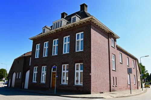a red brick building with white windows on a street at In De Achtste Hemel in Schimmert