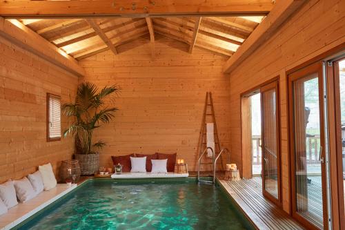 a swimming pool in a house with a wooden ceiling at Hôtel Domaine de Raba Bordeaux Sud in Talence