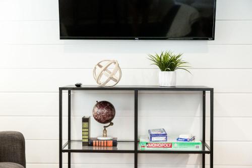 a black shelf with books and a tv on a wall at Lavish Living - 8 mins from Braves Stadium w/King in Smyrna