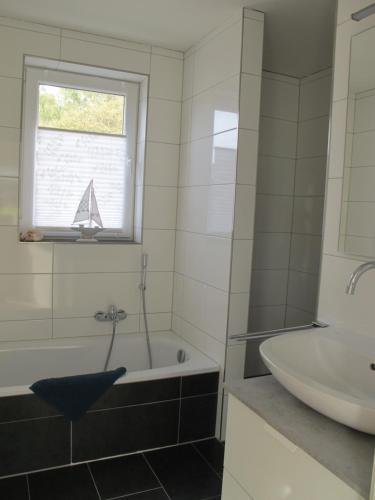a bathroom with a bath tub and a sink at Seestern - Ferienhaus am Quendorfer See (Nr. 5) in Schüttorf