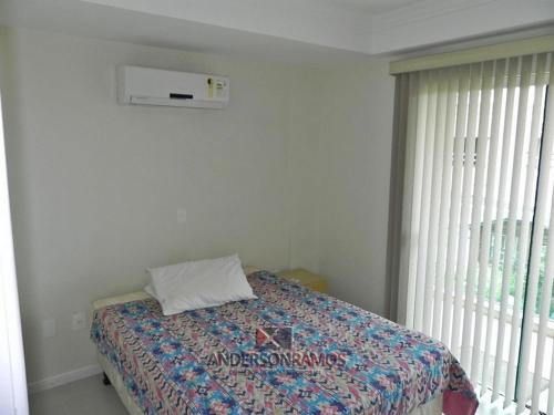 1 dormitorio con cama y ventana en 1028 - Bombinhas para aluguel de temporada - Residencial Areia Branca 201, en Bombinhas