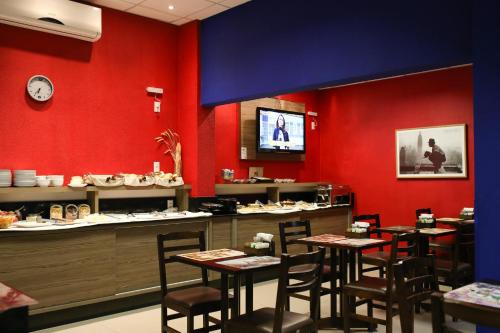 a restaurant with red walls and wooden tables and chairs at Tri Hotel Smart Criciuma in Criciúma