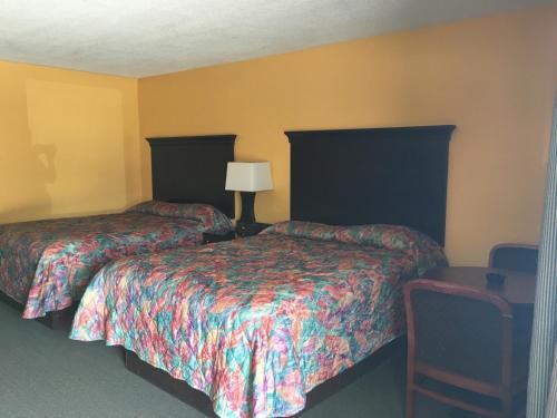 2 Betten in einem Hotelzimmer mit gelben Wänden in der Unterkunft Caronoda Motel in Central City