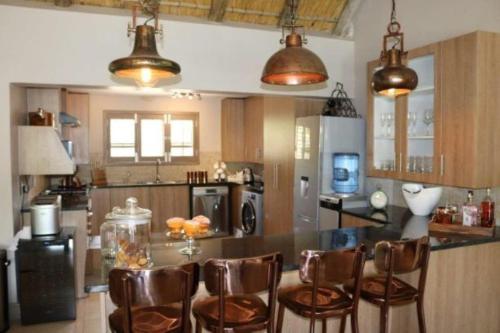 una cocina con mesa y algunas sillas marrones en Luvivane Luxury Villa & Cottage, en Marloth Park