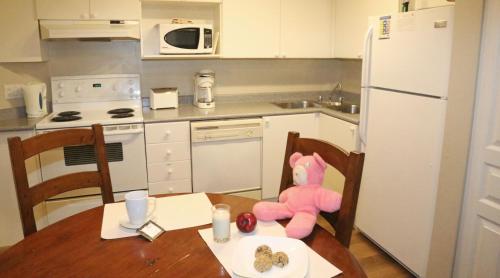 a little girl sitting in a kitchen with a teddy bear at Times Square Suites Hotel in Vancouver