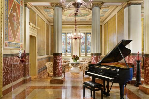 a large room with a piano and a large clock at Villa Cortine Palace Hotel in Sirmione