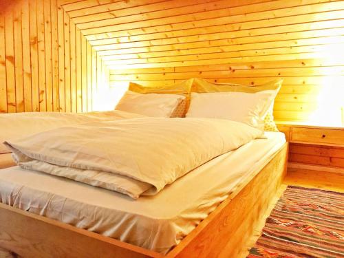 a bed in a room with a wooden wall at Peaceful Nature Cabin Jolly in Mozirje