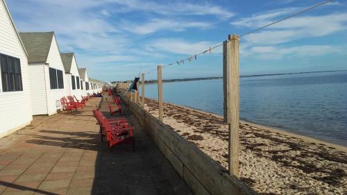 a row of red tables and chairs on a beach at Oceana Cottages in North Truro
