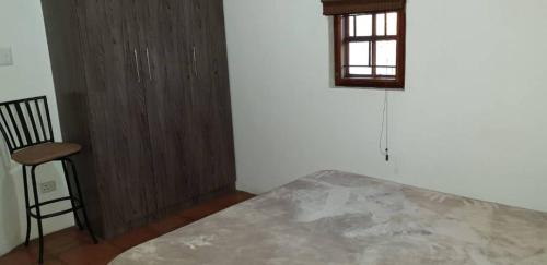a bedroom with a bed and a chair and a window at Nooitgedacht Self Catering CC in Okahandja