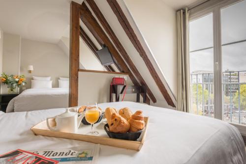 a tray of bread and orange juice on a bed at Hotel Beauvoir in Paris