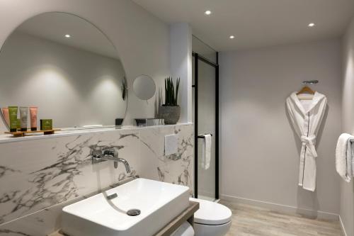 a white bathroom with a sink and a toilet at Citadines Confluent Nantes in Nantes