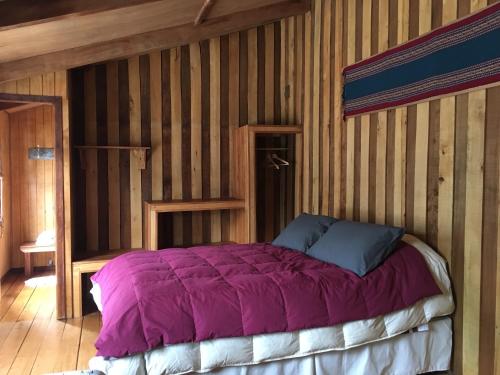 a bedroom with a bed with a purple comforter at La Casona Puelo Lodge in Cochamó