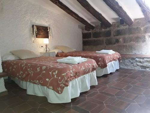 two beds in a room with a brick wall at Lo Cremallé in Valderrobres