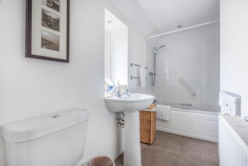 une salle de bain blanche avec un lavabo et une baignoire dans l'établissement Church Farm Cottage, à Cheltenham