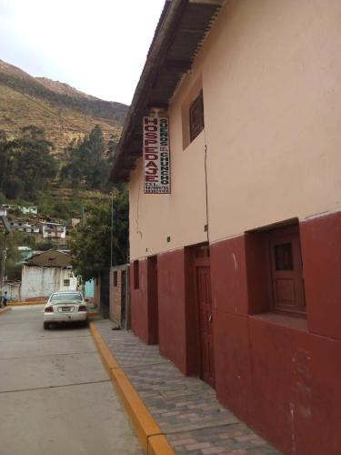 um edifício vermelho e branco com um carro estacionado numa rua em Hotel Sueños del Chuncho em Yauyos