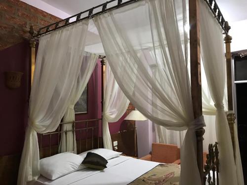 1 dormitorio con cama con dosel y cortinas blancas en Rezeiky Hotel & Camp, en Luxor
