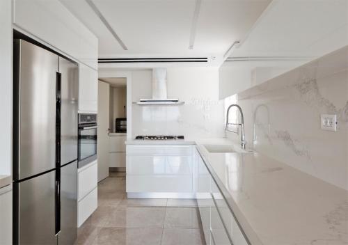 a white kitchen with a stainless steel refrigerator at Oַ&O Group- Mini Penthouse 3BR Sea View Bat-Yam in Bat Yam