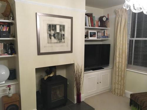 sala de estar con chimenea y TV en Tranquil, luxurious double bedroom, en-suite, cosy private lounge, woodburner & your own front door, en Henley on Thames