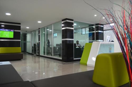an office with green chairs and a person in the background at Hotel Genova Prado in Barranquilla