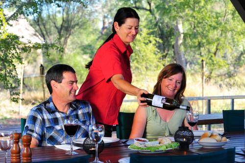 a woman pouring a glass of wine at a table at Bungle Bungle Wilderness Lodge in Turkey Creek