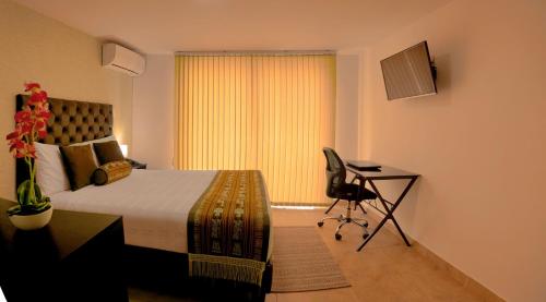 a bedroom with a bed and a desk and a chair at Hotel Alamos Del Parque in Pereira