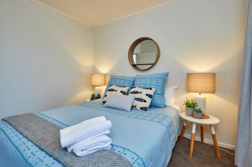a bedroom with a blue bed and a mirror at Seas The Day In Kaikoura - Book Now! in Kaikoura