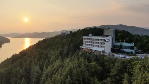 a building on a hill next to a body of water at Asia Lakeside Hotel in Jinju