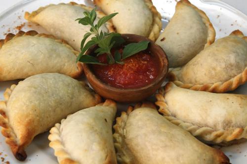 a plate of empanadas with a salsa in a sauce at Patios de Cafayate - Wine Hotel & Restaurant in Cafayate